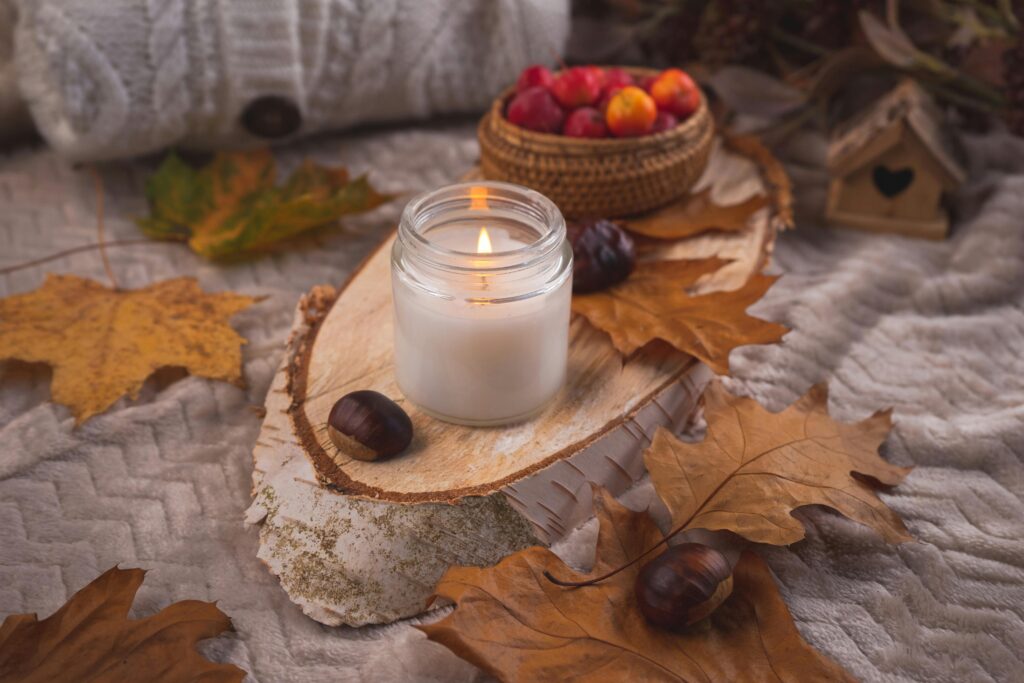 pexels-photo-29196581-29196581 Warm autumn scene with candle, leaves, chestnuts, and cozy textures.