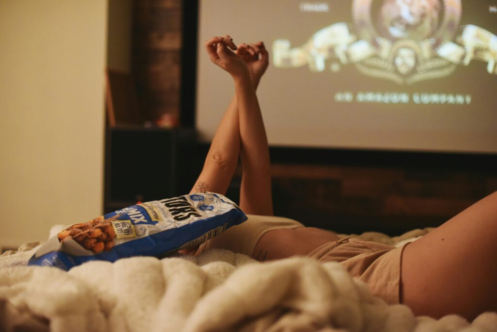 pexels-photo-33381191-33381191 Relaxing movie night at home, lying in bed with snacks and a projector.