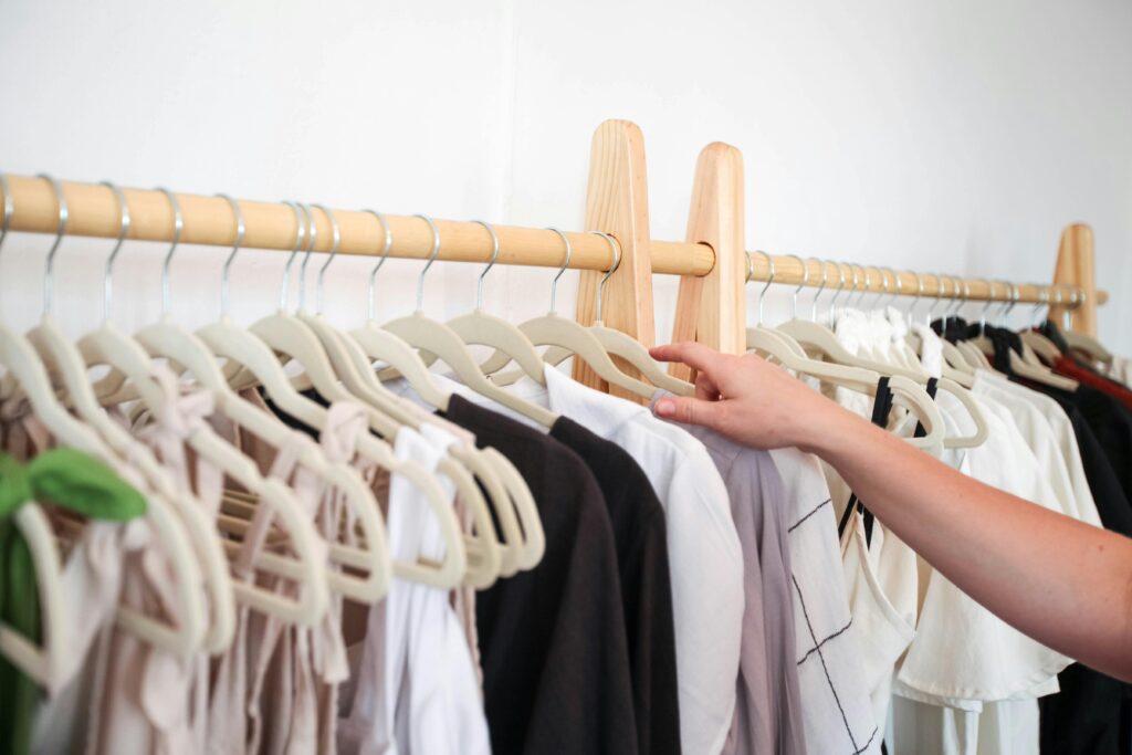 pexels-photo-8030171-8030171 A person choosing clothing from a neatly arranged wardrobe rack indoors.